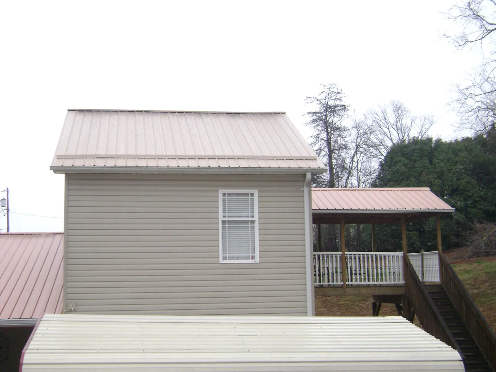 Tan metal roofs on a two story addition and attached porch, from a Roof Replacement job in Luke Air Force Base